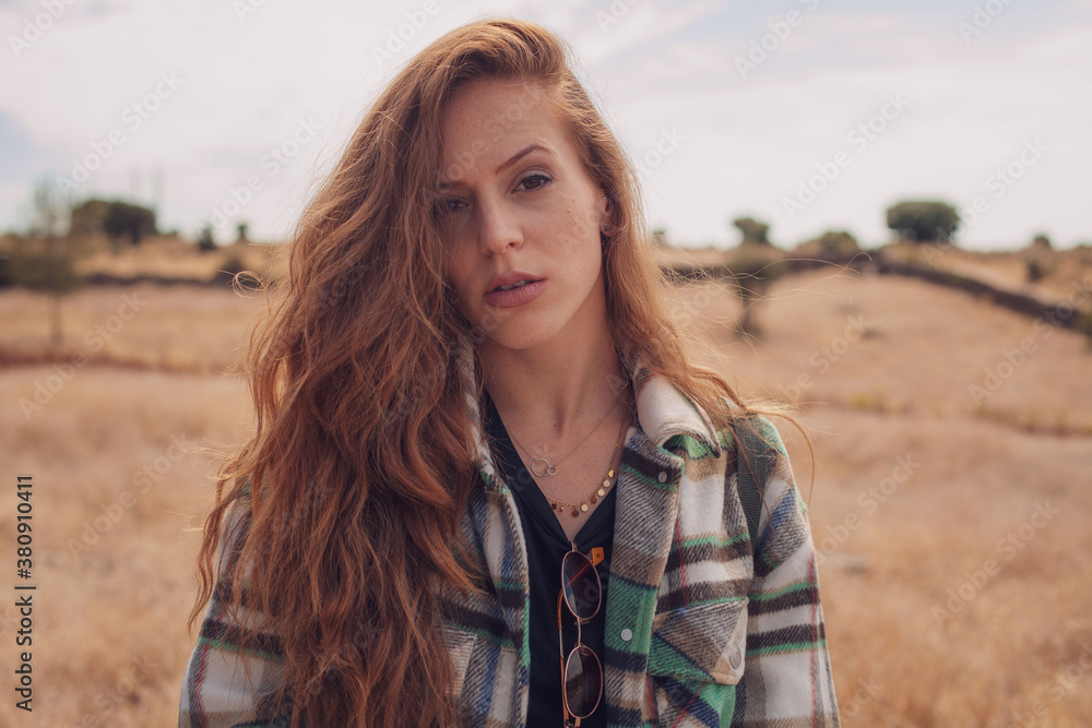 A young girl looking to the camera with a field at her background A young girl looking to the camera with a field at her background