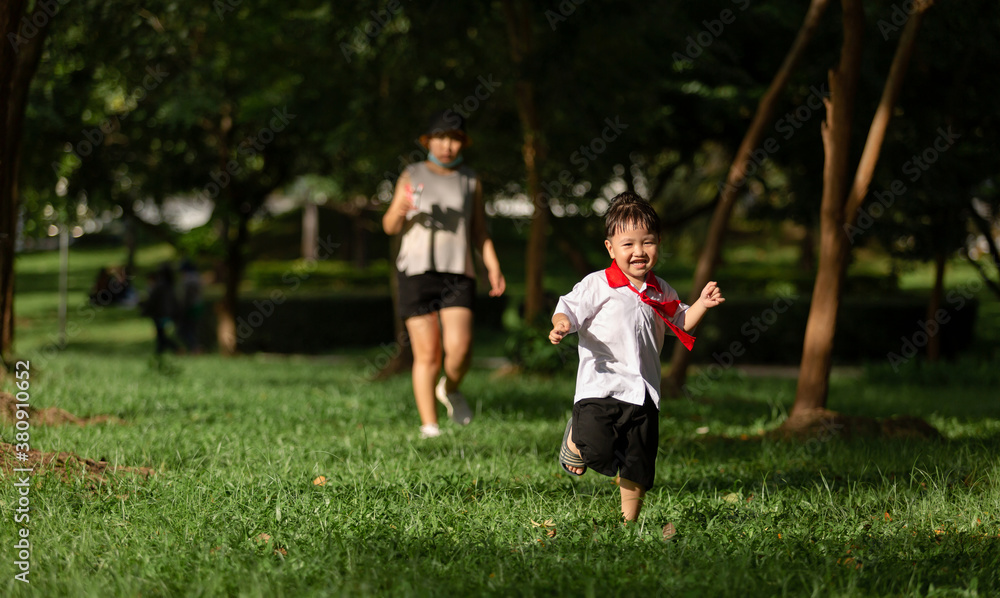 Cute boy running across grass and smiling.
