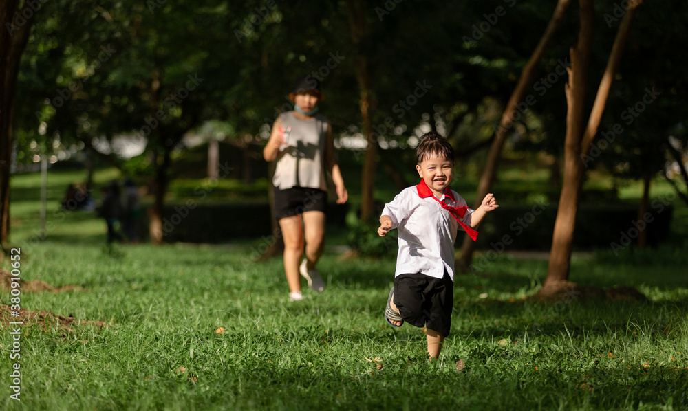 Fototapeta premium Cute boy running across grass and smiling.