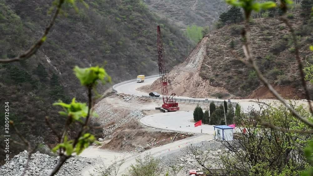 A crane dropping a large weight to flatten earth for a road in the mountains of China near the Great Wall of China A crane dropping a large weight to flatten earth for a road in the mountains of China near the Great Wall of China