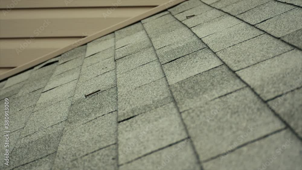 Walking up a roof, blonde shingles with siding along the back of the image. Walking up a roof, blonde shingles with siding along the back of the image.