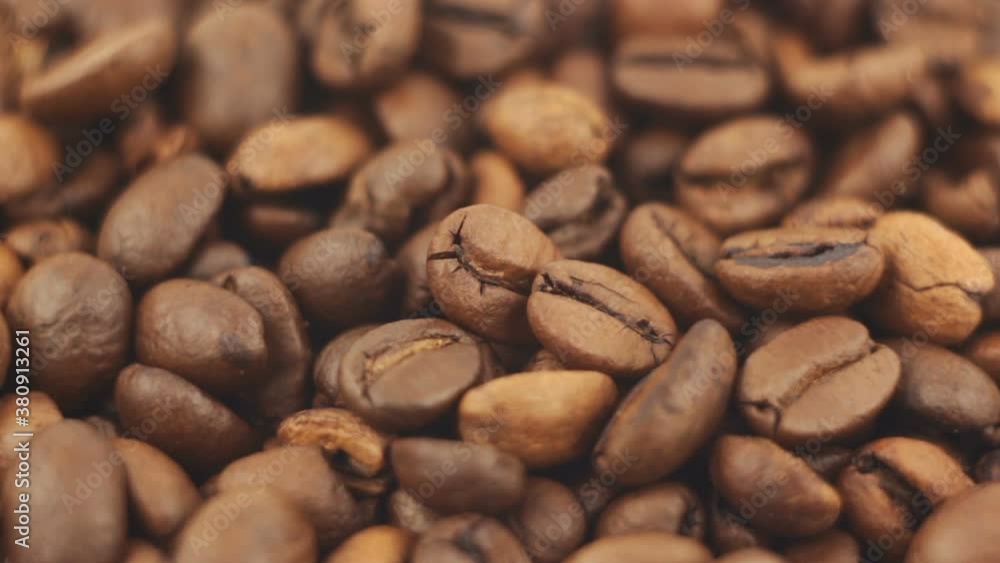 Roasted grains of aromatic coffee rotate on a plate. Close-up of the rotation of coffee beans. Roasted grains of aromatic coffee rotate on a plate. Close-up of the rotation of coffee beans.