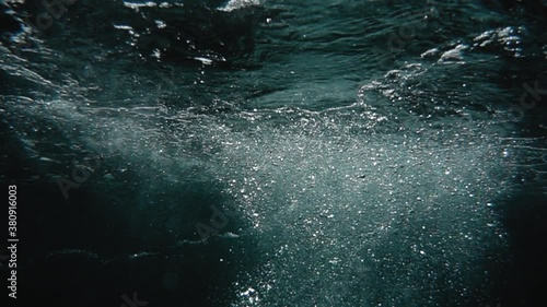 Bubbles rise from the depth to the surface in slow motion. They turbulize and dissolve in water. They pass close to the camera and propagate in defocus. 