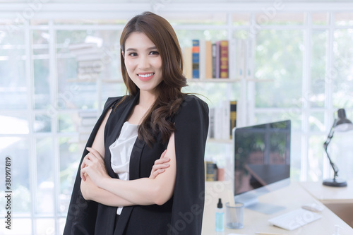 Asian confident woman is standing and arm crossing with smiling face in working room as a background. Free Download Asian confident woman is standing and arm crossing with smiling face in working room as a background. - GFXLoad