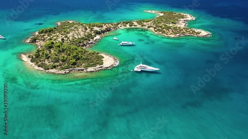 Aerial drone video of Hinitsa island bay a popular anchorage crystal clear turquoise sea bay for yachts and sailboats next to Porto Heli, Saronic gulf, Greece photo