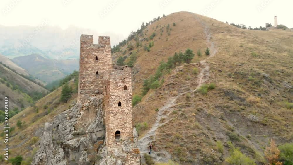 Shooting with quadrocopter shooting an old castle on mountain and path to it. Old abandoned tower on rise to mountain Shooting with quadrocopter shooting an old castle on mountain and path to it. Old abandoned tower on rise to mountain