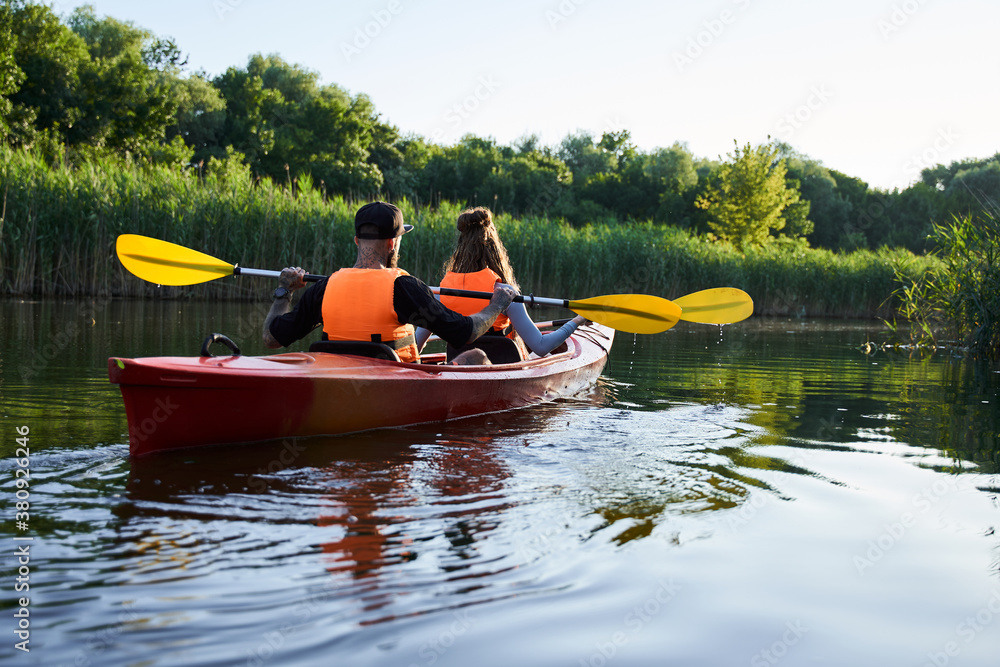 Fototapeta premium Couple kayaking on river at evening