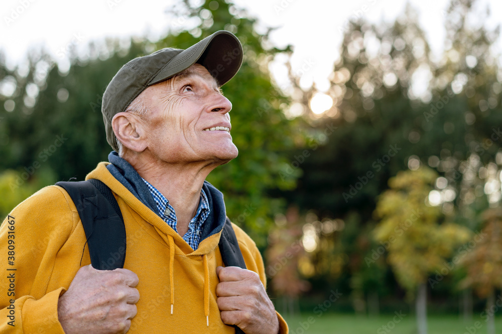 Obraz premium wisdom senior hiker man with packback looking on top of high mountain autumn forest background
