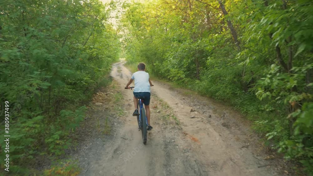 A happy child rides a bicycle in a park in the open air. Cycling on a path in the woods. Active rest of the child. Healthy lifestyle, children's sports. A happy child rides a bicycle in a park in the open air. Cycling on a path in the woods. Active rest of the child. Healthy lifestyle, children's sports.