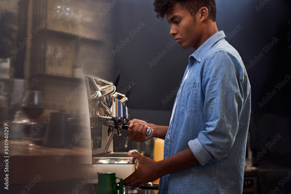Serious male barista making coffee