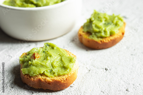 Crostini or bruschetta with traditional mexican appetizer guacamole and a bowl close-up on the gray background