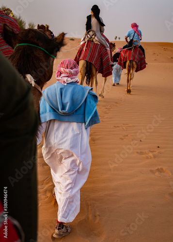 Guides leading tourists on a camel safari in the desert outskirts of Dubai, United Arab Emirates (UAE)