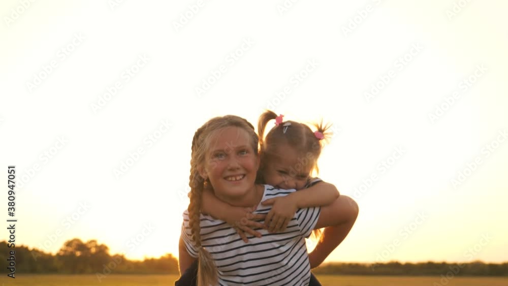 Happy family in the park. Kids play in the park at sunset. Children play as an airplane pilot. Child dreams of becoming a pilot. Little Girl sits on her sister's back. Happy emotions of kids faces. Happy family in the park. Kids play in the park at sunset. Children play as an airplane pilot. Child dreams of becoming a pilot. Little Girl sits on her sister's back. Happy emotions of kids faces.