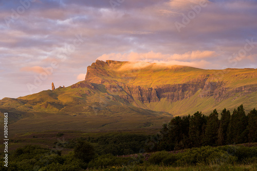 The Old Man of Storr seen from distance - famous rocky formation in Trotternish landslip, Isle of Skye, Scotland. Rocky pinnacle, surrounded by majestic landscape and beautiful clouds during sunrise