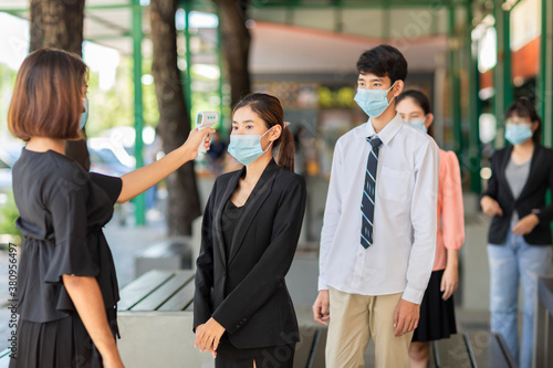 Office workers standing in line must go through fever measures using infrared digital thermometer check temperature measurement on the forehead during the coronavirus pandemic. Covid-19.