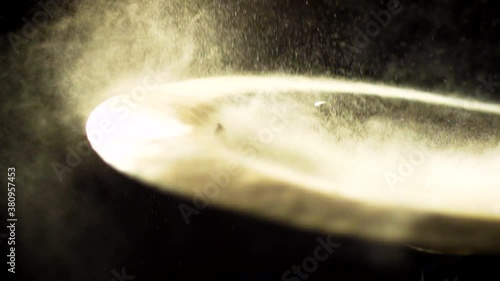 A camera moves in on a crash cymbal covered in dust as it gets hit in slow motion. photo