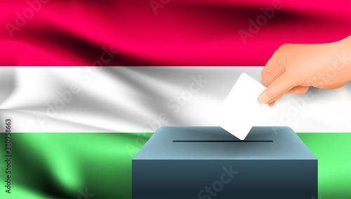 Male hand puts down a white sheet of paper with a mark as a symbol of a ballot paper against the background of the Hungary flag. Hungary the symbol of elections
