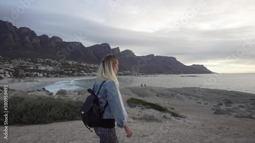 Young Woman walking in Cape Town, South Africa in Slow Motion, enjoying the view of Camps Bay and Table Mountain from Maidens Cove during Sunset