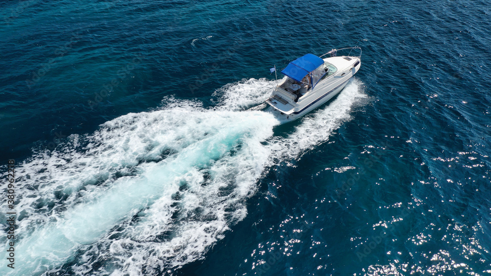Naklejka premium Aerial drone photo of luxury power boat cruising in deep blue sea near Mediterranean Aegean island