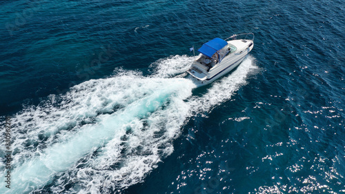 Aerial drone photo of luxury power boat cruising in deep blue sea near Mediterranean Aegean island