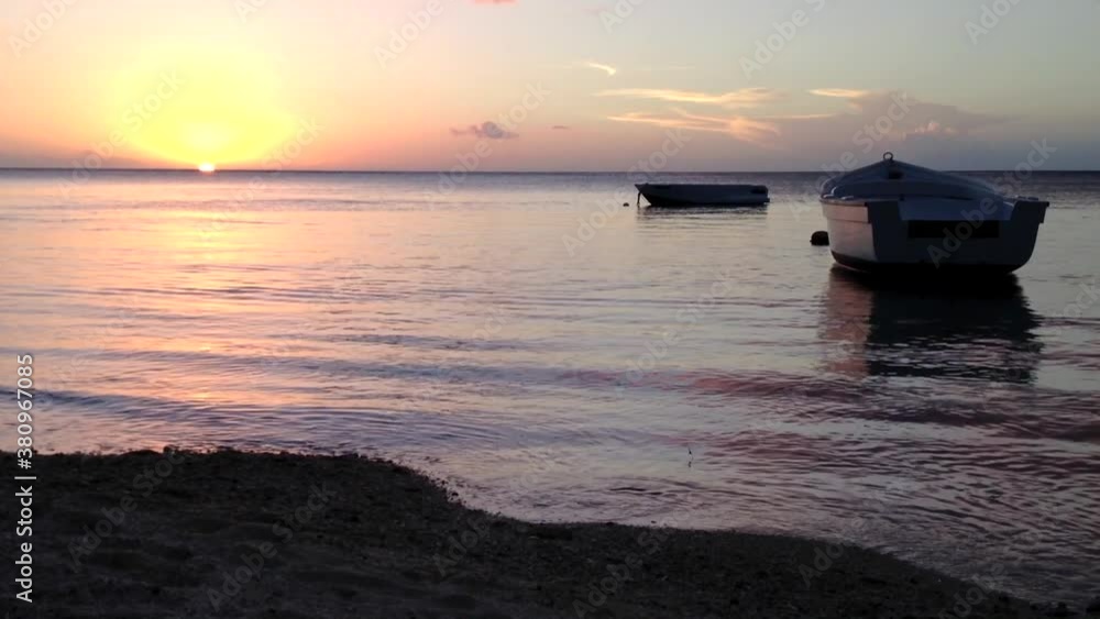 Small boats at sunset with sea waves breaking on the shore Small boats at sunset with sea waves breaking on the shore