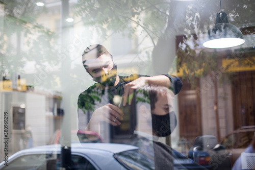 Man getting hair cut at the barber shop wearing protective mask during coronavirus pandemic