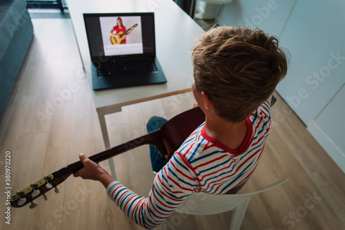 Fototapeta young boy having guitar lesson online at home