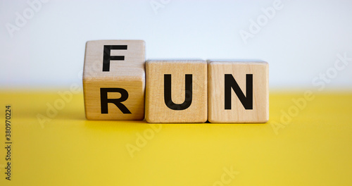 Hand is turning a cube and changes the word Fun to Run. Beautiful yellow table, white background. Lifestyle concept, copy space.