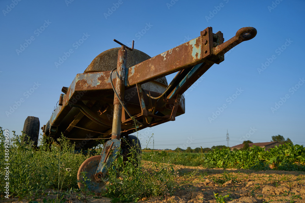 Fototapeta premium Old manure trailer, rusted drawbar in focus. Vegetable field.