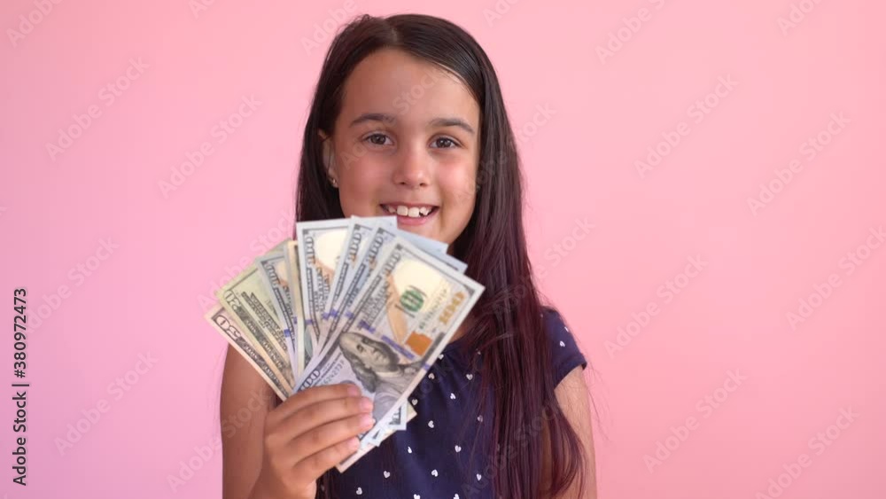 Little caucasian child girl receives money income in banknotes dollar cash. Happy kid having fun, smiling, looking at camera. Little caucasian child girl receives money income in banknotes dollar cash. Happy kid having fun, smiling, looking at camera.