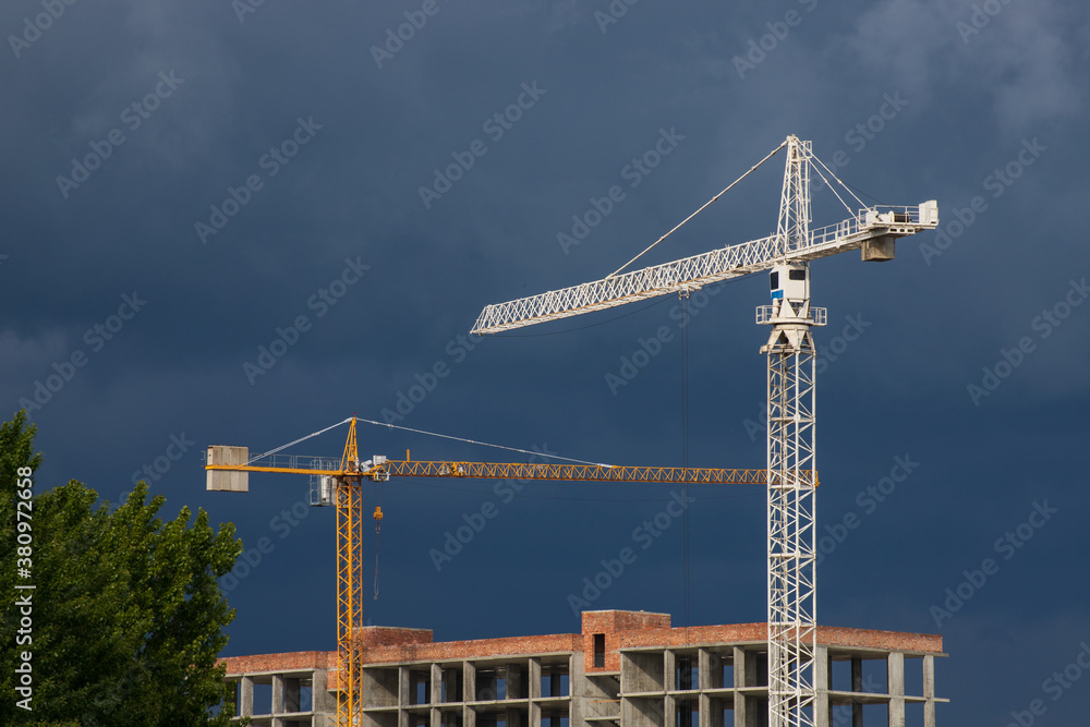 Construction cranes in the contrasting sky Construction cranes in the contrasting sky