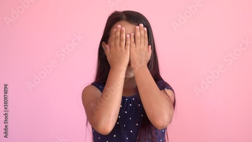 Girl playing hide and seek portrait. Cute little girl open her face with hands. Playing hide and seek, peek a boo. Closeup.
