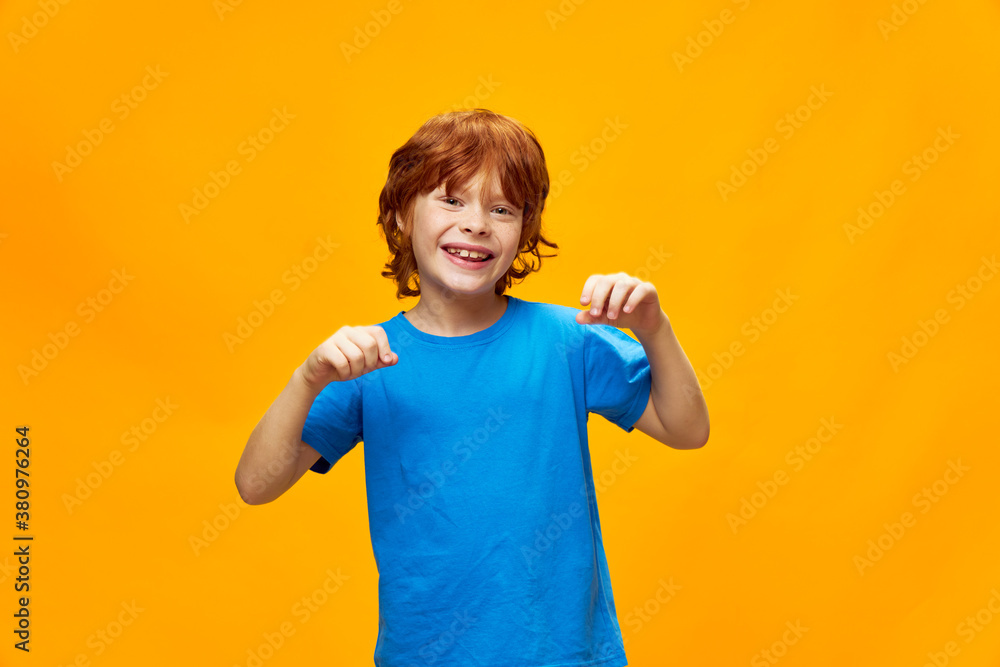 smiling redhead boy holding his hands in front of him gesturing with his hands yellow isolated background smiling redhead boy holding his hands in front of him gesturing with his hands yellow isolated background