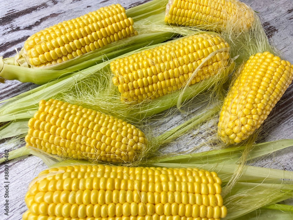 Close-up of ripe raw corn swings on an abstract wooden surface.The concept of proper healthy nutrition, agriculture. Close-up of ripe raw corn swings on an abstract wooden surface.The concept of proper healthy nutrition, agriculture.