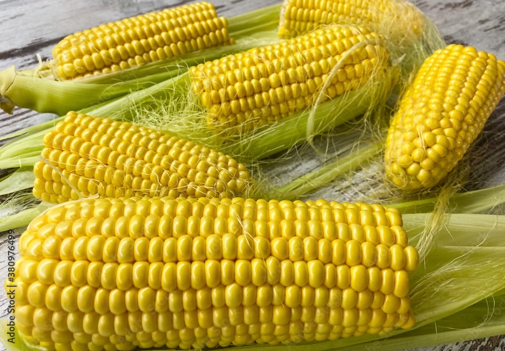 Close-up of ripe raw corn swings on an abstract wooden surface.The concept of proper healthy nutrition, agriculture. Close-up of ripe raw corn swings on an abstract wooden surface.The concept of proper healthy nutrition, agriculture.