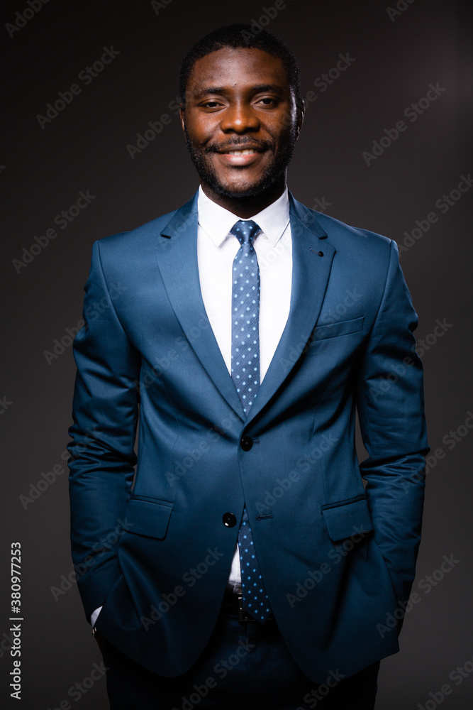 Portrait of an african american businessman man in blue classic suit who stands on gray background Portrait of an african american businessman man in blue classic suit who stands on gray background