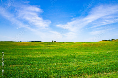Beautiful summer bright green meadow and field with blue sky. Empty landscape