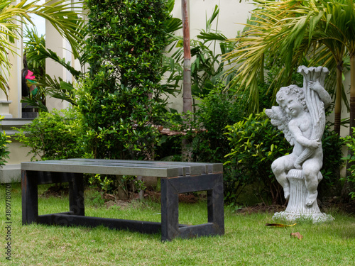 garden chair, white cupid statue. On green grass in the park in Bangko photo