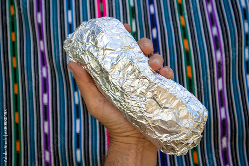 Large Whole California-style Burrito Wrapped in Foil being held in a Hand
