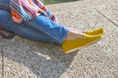 woman legs in yellow moccasins against the background of a concrete wall photo