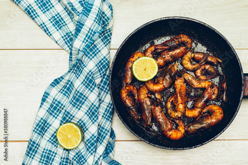 Delicious roasted grilled shrimps on pan with lemon slice and napkin