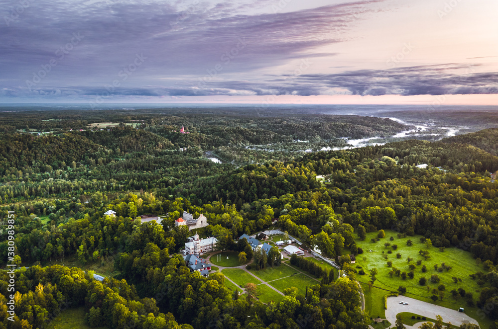 Picturesque valley of Sigulda city in sunrise colors. Panoramic view over pine forest surrounding river Gauja.