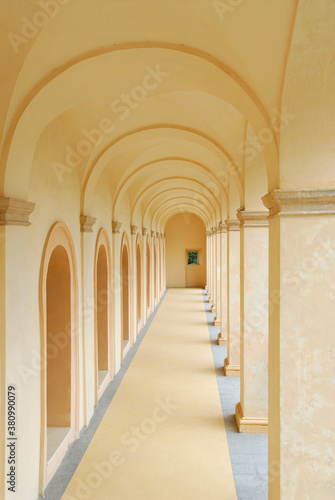 Hallway with arches at La Rocca Spoleto leading to a window of green