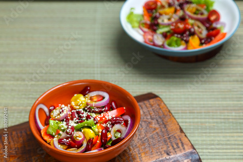 Two Plates with Pan-Asian salad with sesame seeds and tamarind on wooden stands.