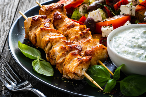 Fried souvlaki, greek salad and tzatziki on wooden table