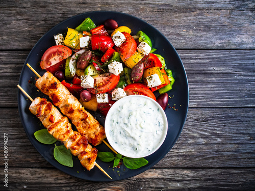 Foto Fried souvlaki, greek salad and tzatziki on wooden table