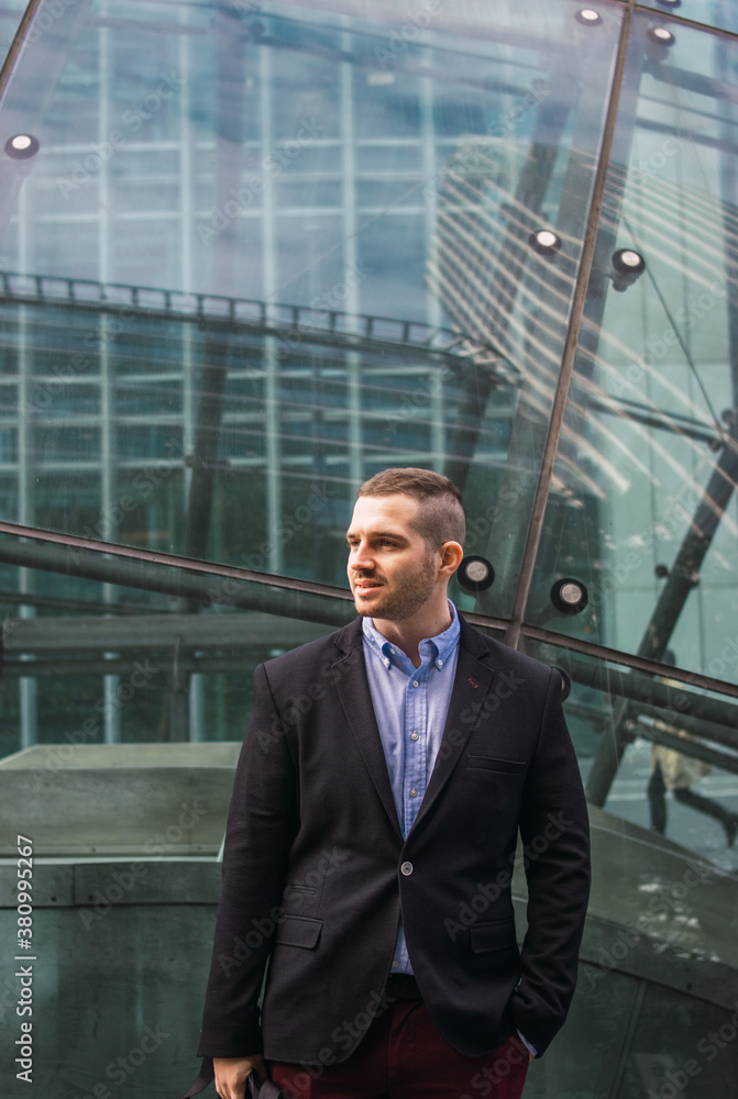 Photo of a young and attractive businessman wearing smart casual clothes and with a business building on the back. Photo of a young and attractive businessman wearing smart casual clothes and with a business building on the back.