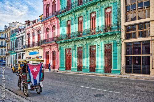 A tricycle taxi riding along beautiful colourful buildings in Havana Cuba