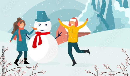 Winter activities concept. A young couple of a guy and a girl are making a snowman together enjoying the falling snow and winter nature on the background of a country landscape.