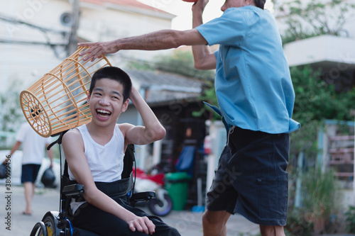 Asian special child on wheelchair playing chair ball/ basketball to strengthen muscles,Lifestyle of disabled child,Life in the education age of children,Happy disability kid with home school concept.